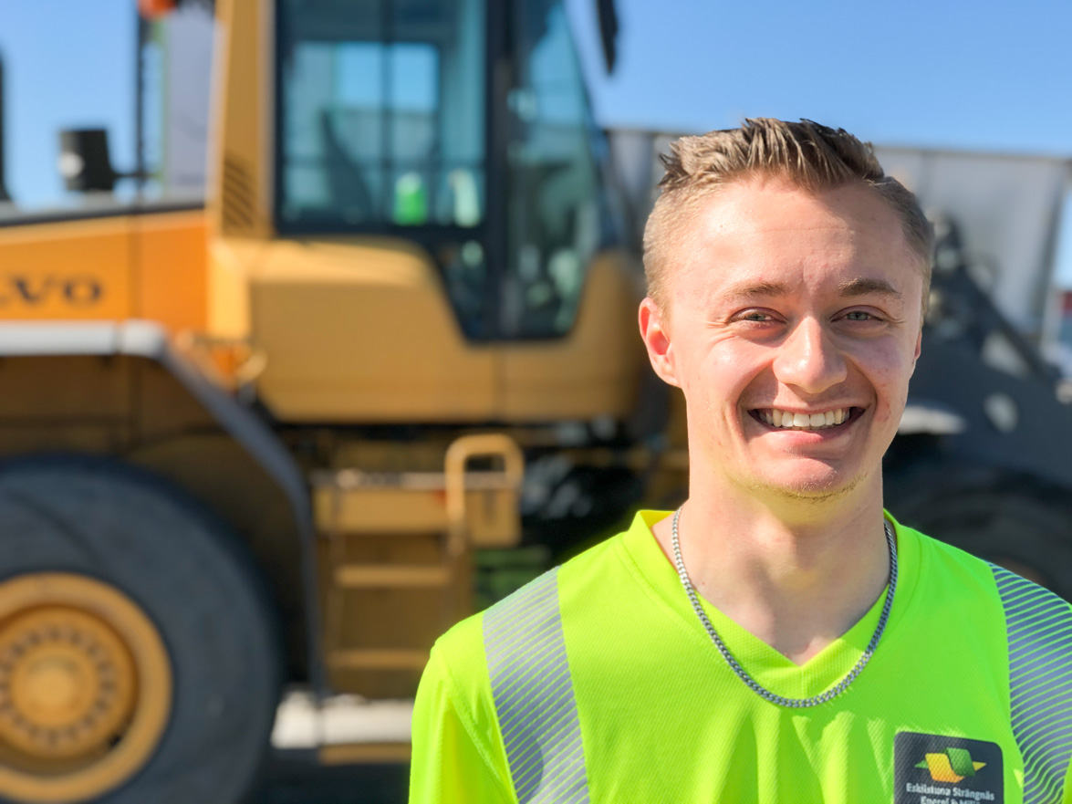 Bild på Benjamin Eriksson framför arbetsfordon